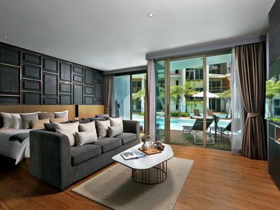 Camera d'hotel moderna con letto matrimoniale, divano e vista sulla piscina attraverso ampie finestre.