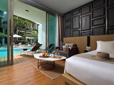 Camera d'hotel moderna con letto ampio, arredamento lounge e vista sulla piscina