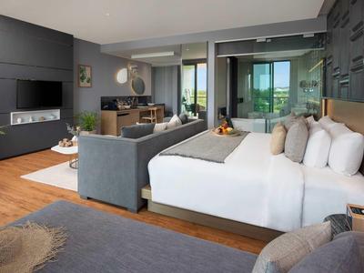 Camera d'hotel moderna con letto grande, divano, scrivania e balcone con vista.