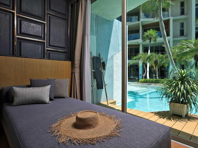 Camera d'hotel moderna con letto singolo e vista sulla piscina e il giardino.