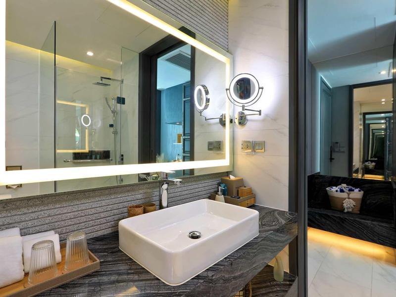 Bagno d'hotel moderno con specchio illuminato e elegante lavabo.