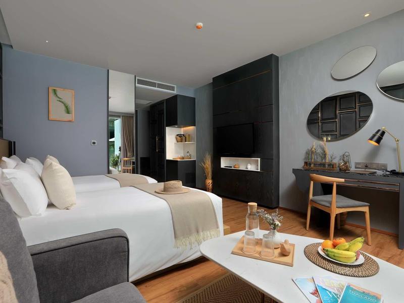 Camera d'hotel moderna con letto grande, camino e scrivania in tonalità neutre.