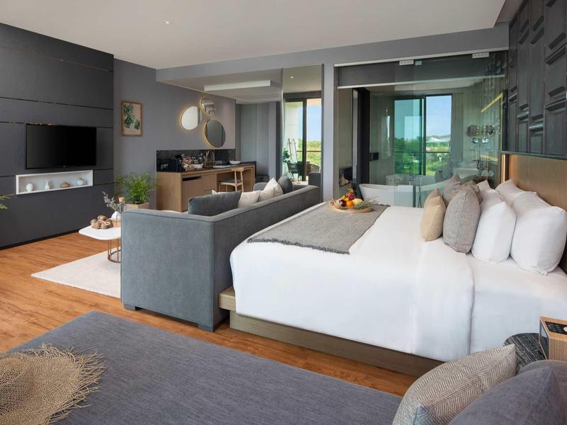 Camera d'hotel moderna con letto grande, divano, scrivania e balcone con vista.