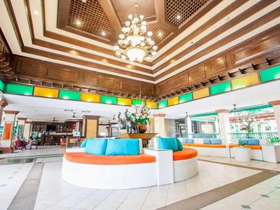 Hall d'hotel moderno con sedute circolari e lampadario sotto soffitti in legno.