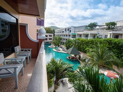 Balcone con sedie che si affaccia su una piscina tropicale e complesso alberghiero.