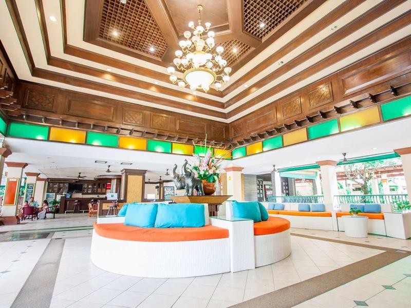 Ampia hall dell'hotel con divano rotondo colorato e lampadario sotto soffitto in legno.