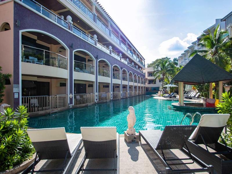 Hotel con piscina lunga, lettini e palme in una giornata di sole