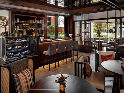 Interior moderno de bar y restaurante con muebles de madera y grandes ventanas que dan al exterior.