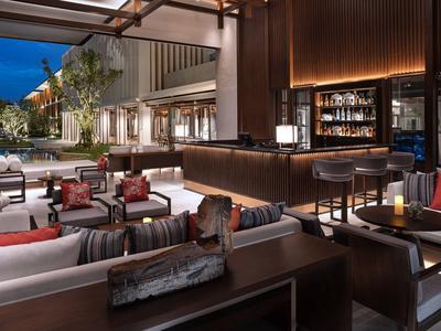 Área moderna de bar y salón de hotel con asientos cómodos y iluminación ambiental por la noche.