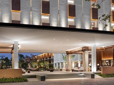 Entrada moderna de hotel con techo iluminado y área de recepción acogedora al atardecer.