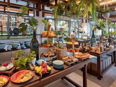 A buffet with various pastries, fruits, and fresh herbs in a bright, elegant room with large windows.