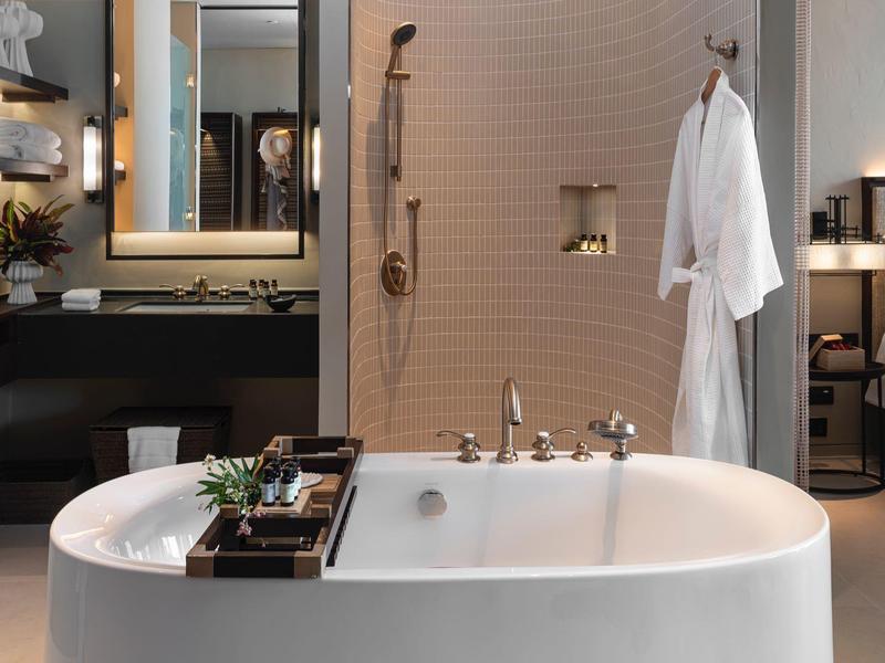 Elegante baño con bañera exenta, espejo iluminado y área de ducha moderna.