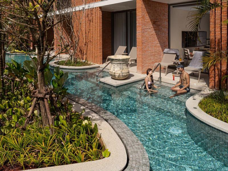 Área de descanso junto a la piscina de un hotel con ambiente natural y relajado.