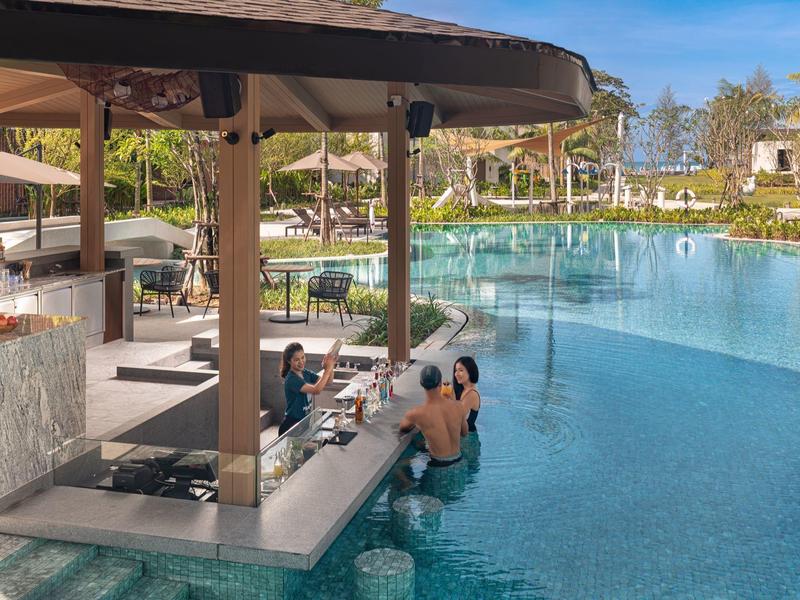 Piscina con bar integrado y huéspedes sentados en el agua relajándose.