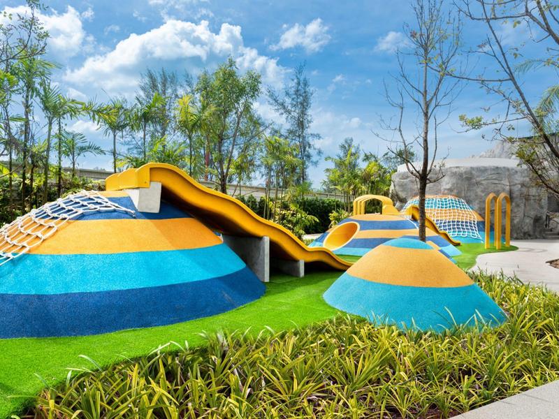 Parque de juegos al aire libre con estructuras coloridas en un entorno natural soleado.