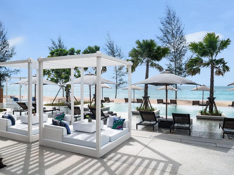 Espacio relajante al aire libre con camas balinesas, sombrillas y vista al mar en un resort de playa.