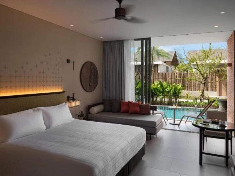 Habitación de hotel moderna con cama doble, sofá y vista a piscina privada y jardín.