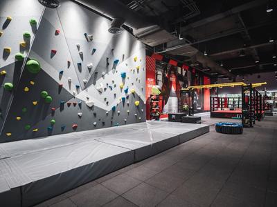 Wnętrze hali wspinaczkowej z kolorowymi chwytami i wyściełaną matą podłogową