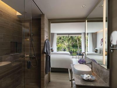 Nowoczesny pokój hotelowy z podwójnym łóżkiem, dużymi oknami i łazienką z szklaną prysznicem.