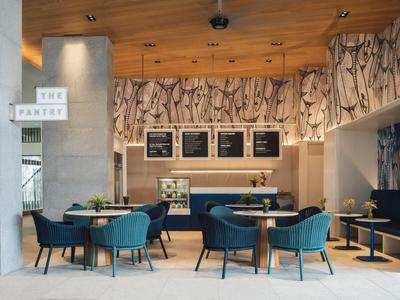 Przytulna jadalnia z niebieskimi fotelami, drewnianymi stołami i dekoracyjnymi ścianami z wzorem drewna.