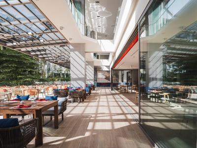 Nowoczesna restauracja hotelowa z dużą ilością naturalnego światła, przytulnymi miejscami do siedzenia i szklanym dachem.