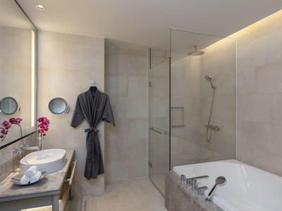 Nowoczesna łazienka z wanną, prysznicem, podwójnymi umywalkami i szarym szlafrokiem.