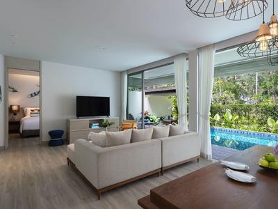 Nowoczesny salon z sofą, telewizorem i widokiem na basen i ogród przez duże okna.