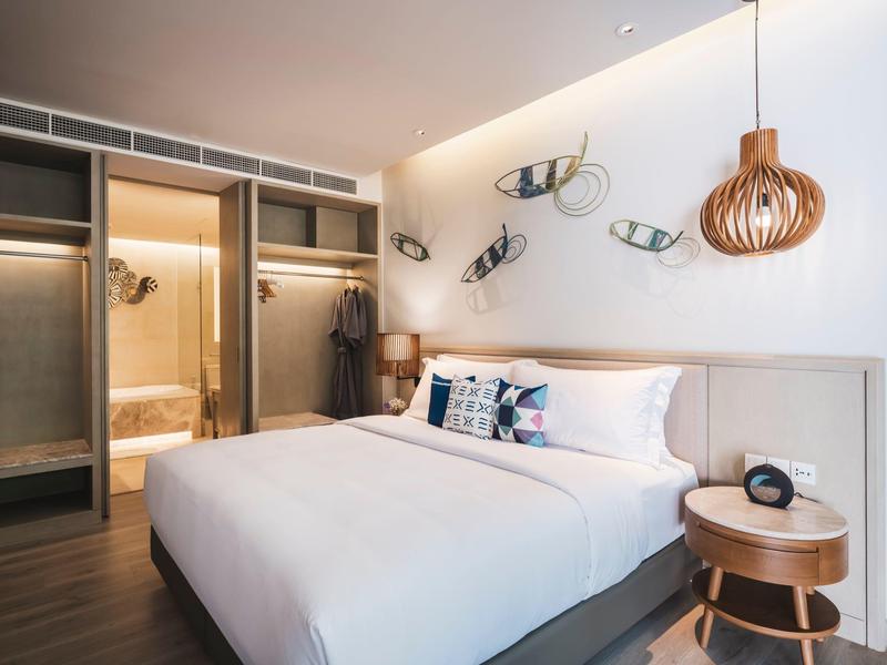 Przytulny pokój hotelowy z dużym łóżkiem, drewnianym wystrojem i nowoczesnym oświetleniem.