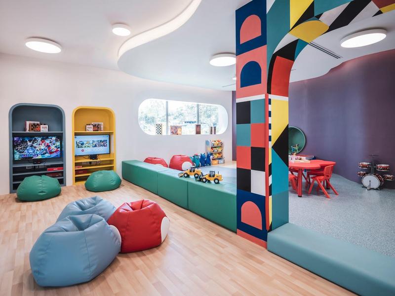 Kolorowy kącik zabaw dla dzieci z workami do siedzenia, zabawkami i konsolami do gier w nowocześnie urządzonym pokoju.