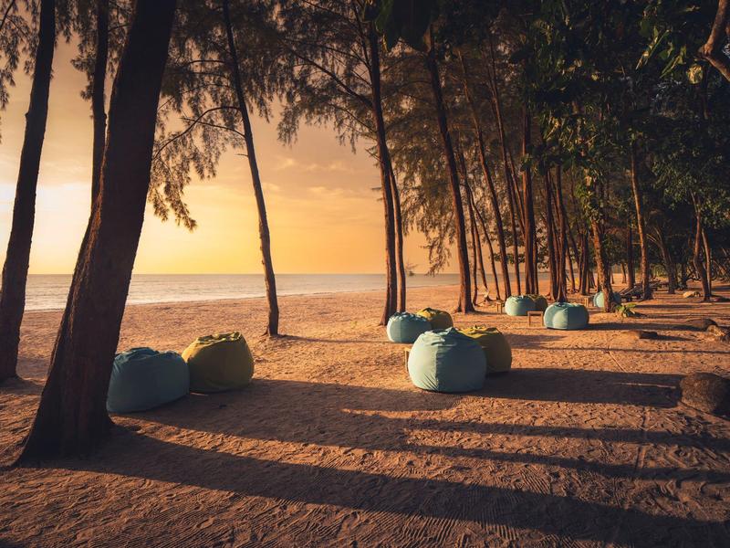 Plaża z workami do siedzenia pod drzewami o zachodzie słońca.