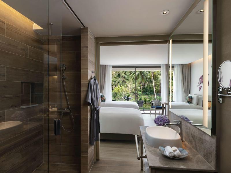 Nowoczesny pokój hotelowy z podwójnym łóżkiem, dużymi oknami i łazienką z szklaną prysznicem.