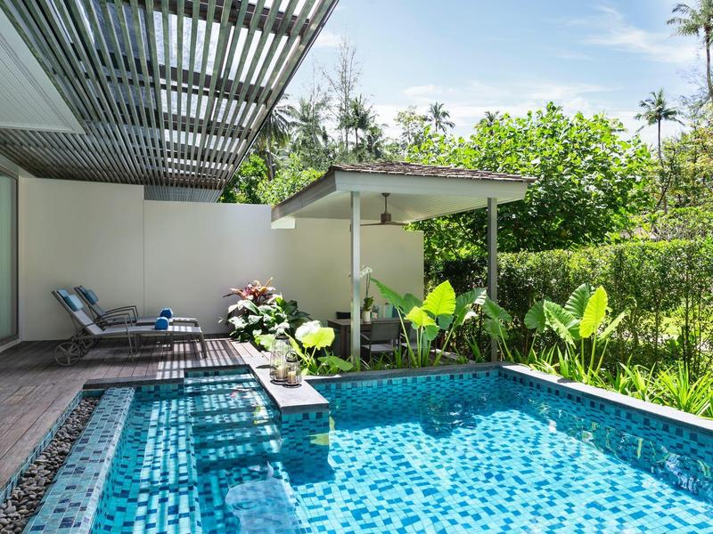 Nowoczesny basen na zewnątrz z leżakami na tarasie i zielonymi roślinami w tle