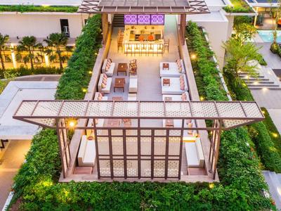 Espace extérieur moderne avec mobilier lounge, entouré de plantes et d’éclairage dans un hôtel.