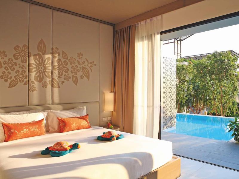 Světle zařízená ložnice s manželskou postelí a výhledem na soukromý bazén a zahradu.