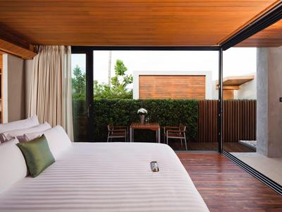 Moderní hotelový pokoj s velkou postelí, dřevěnou podlahou a výhledem na terasu se zahradou