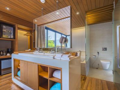 Moderní koupelna s dvojitým umyvadlem, dřevěným stropem a velkým skleněným sprchovým koutem.