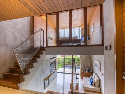 Moderní interiér s otevřeným schodištěm a velkou skleněnou stěnou, výhled na terasu a zahradu.