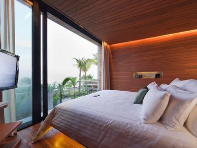 Moderní hotelový pokoj s velkou postelí a balkonem s výhledem na palmy.