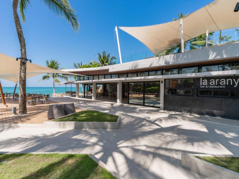 Moderní plážová restaurace s zastřešenou terasou a palmami na slunci