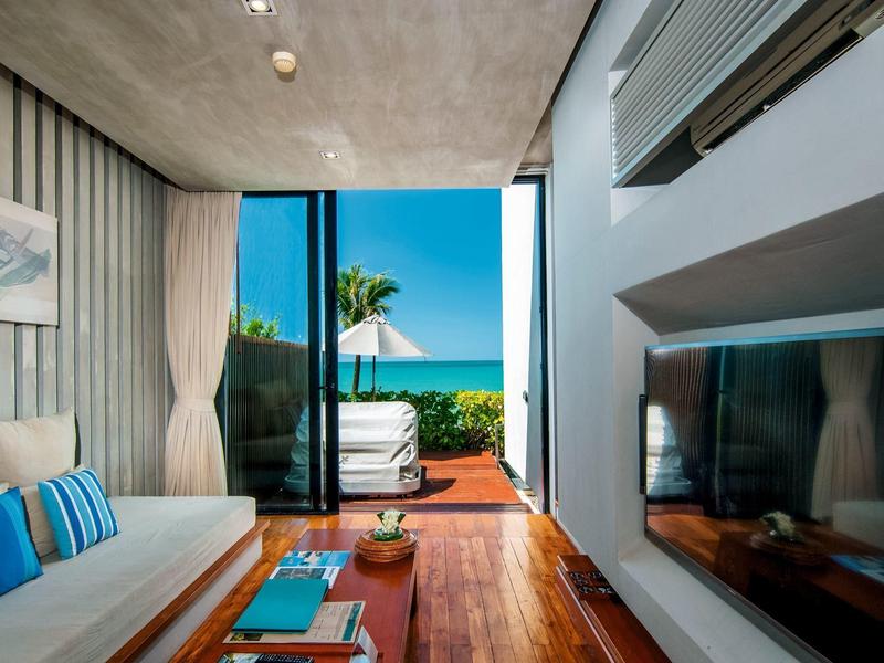 Moderní pokoj s pohodlnou pohovkou a výhledem na terasu a moře.