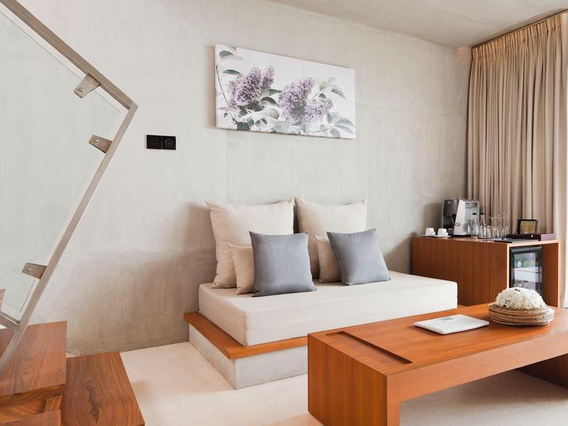 Světý pokoj s moderní pohovkou, dřevěným stolem, schody a balkonem s výhledem na zeleň.