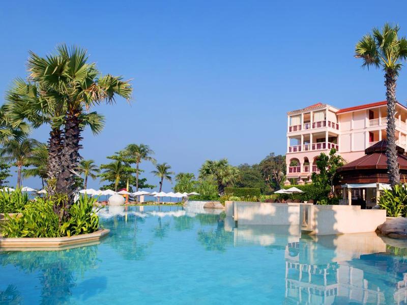 Luksusowy ośrodek z basenem, leżakami, palmami i błękitnym niebem