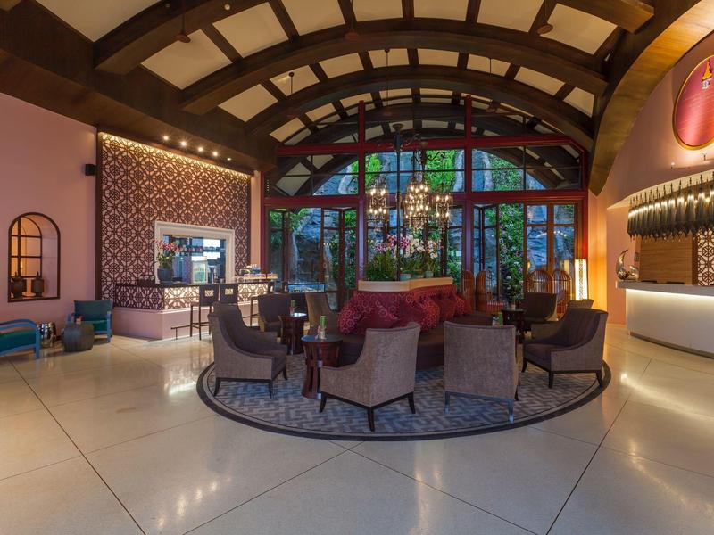 Elegancka lobby hotelowa z łukowym sufitem, żyrandolem, miejscem do siedzenia i dużymi oknami.