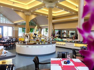 Großer, heller Speisesaal mit runden Tischen, Holzstühlen und dekorativem Buffet im Zentrum.