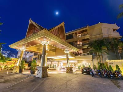 Großes Hotel mit traditionellem Dach bei Nacht, beleuchtet, unter blauem Himmel mit sichtbarem Mond.