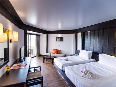 Modernes Hotelzimmer mit zwei Einzelbetten, Holzvertäfelung und gemütlicher Sitzecke.