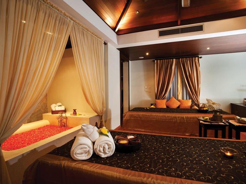 Eleganter Wellnessraum mit Massagebetten, Vorhängen, gedämpftem Licht und dekorativen Kissen.