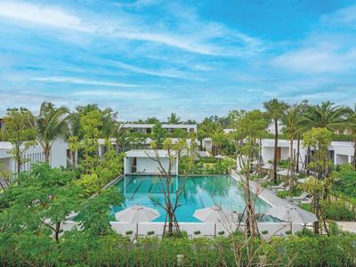 Moderner Hotelpool umgeben von Palmen und grüner Vegetation unter blauem Himmel.