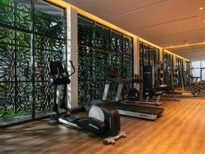 Moderner Fitnessraum mit Trainingsgeräten und vertikalen Pflanzenwänden im Hotel.