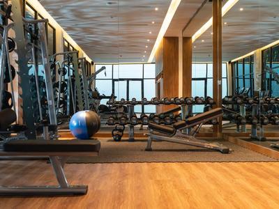 Moderne Fitnessraum mit Holzfußboden, Spiegeln und vielseitigen Trainingsgeräten für Hotelgäste.
